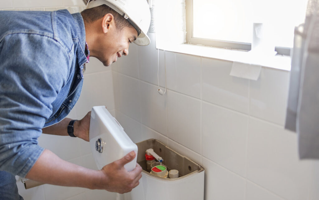 Plumber fixes toilet in a client's home